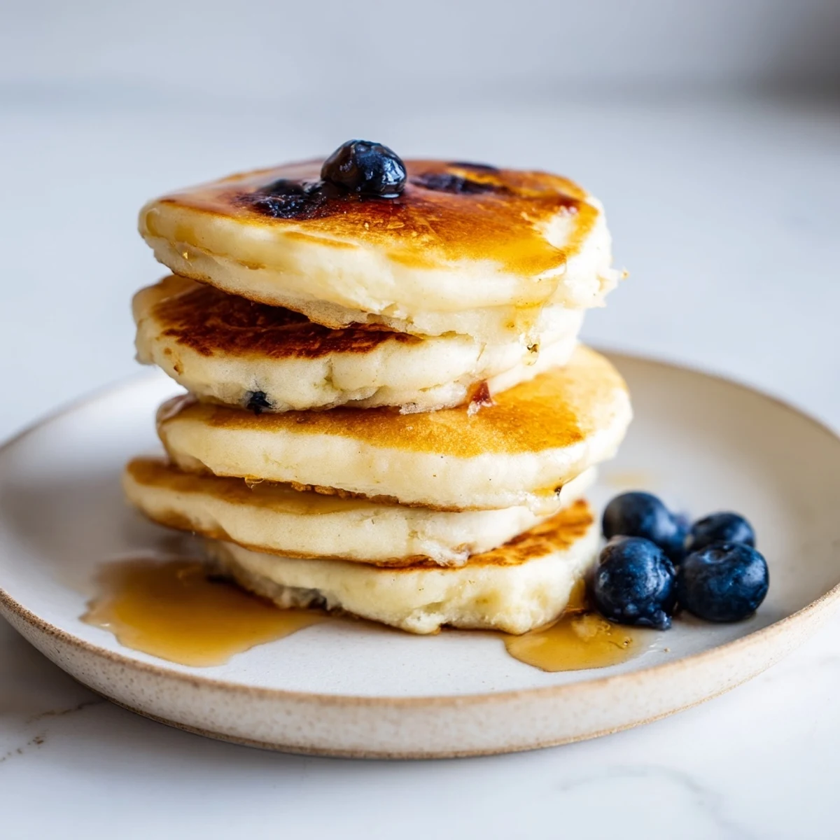 A stack of light and airy ricotta pancakes, topped with fresh berries, ready to enjoy.
