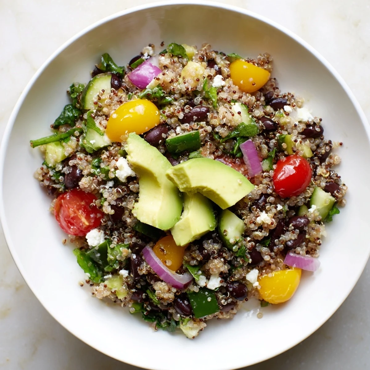 Close-up shot shows a Poppy-Bright Colorful Quinoa and Black Bean Salad garnished with fresh herbs and avocado.