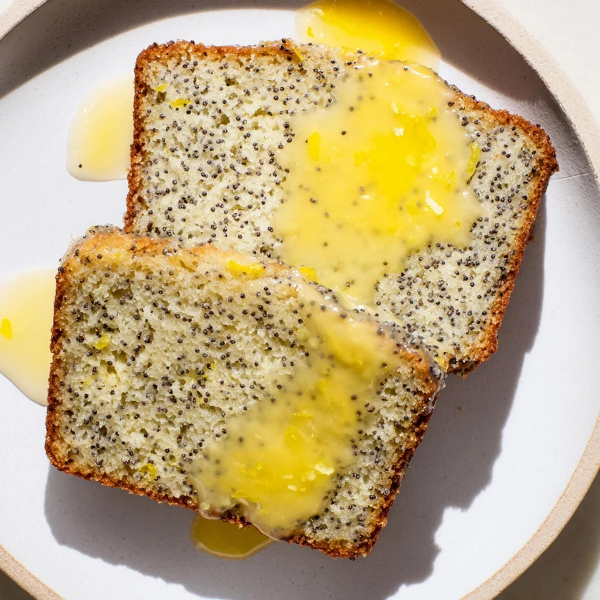 A close-up of a freshly baked Glazed Lemon Poppy Seed Cake, showcasing its light, airy texture.