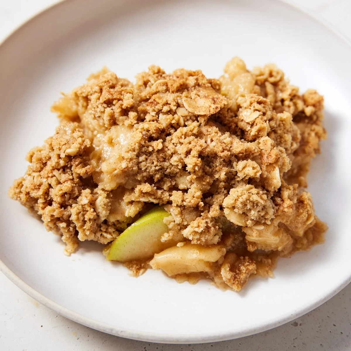 Warm, comforting serving of Soft Crumb Apple Crisp, ready to enjoy with a scoop of vanilla ice cream.