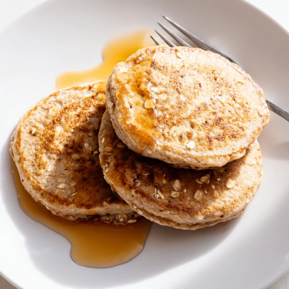 Golden brown banana oat pancakes stacked high, ready for fresh fruit and syrup.
