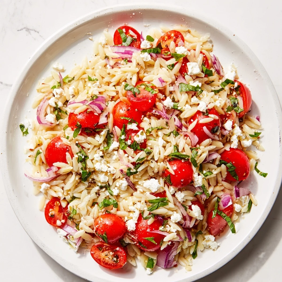 Vibrant Tomato Feta Orzo pasta salad with glistening tomatoes and crumbled feta cheese.