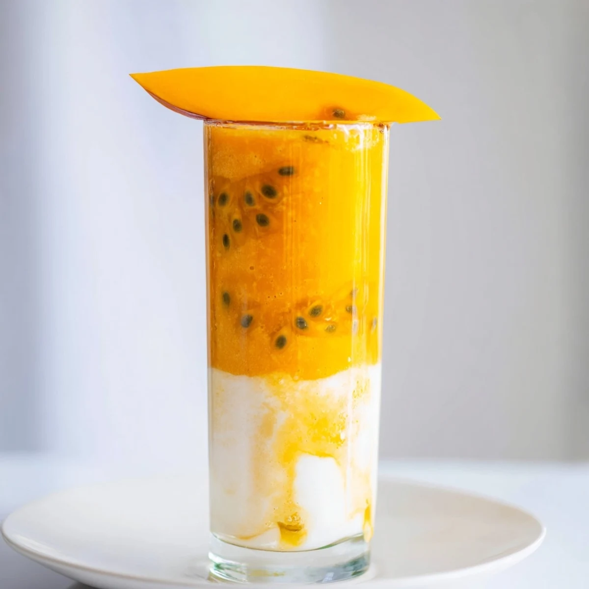 Vibrant layers of mango, passion fruit, and orange juice create this beautiful Tropical Sunset Smoothie.