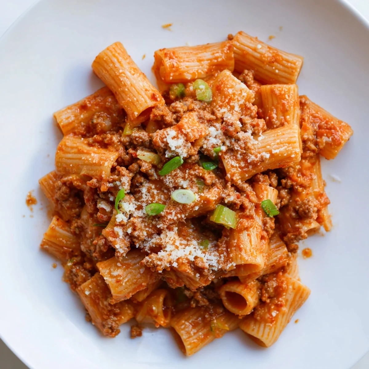 Steaming bowl of Chaos Cooking Kimchi Ragu Pasta, savory and bright, with fresh green scallion garnish.