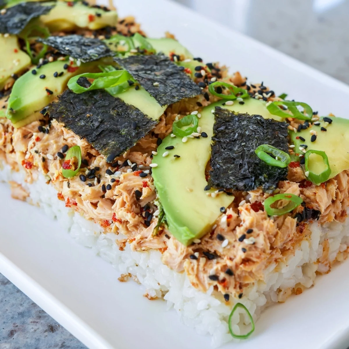 Warm and inviting image of a baked Sushi Bake Casserole, topped with avocado and sesame seeds.
