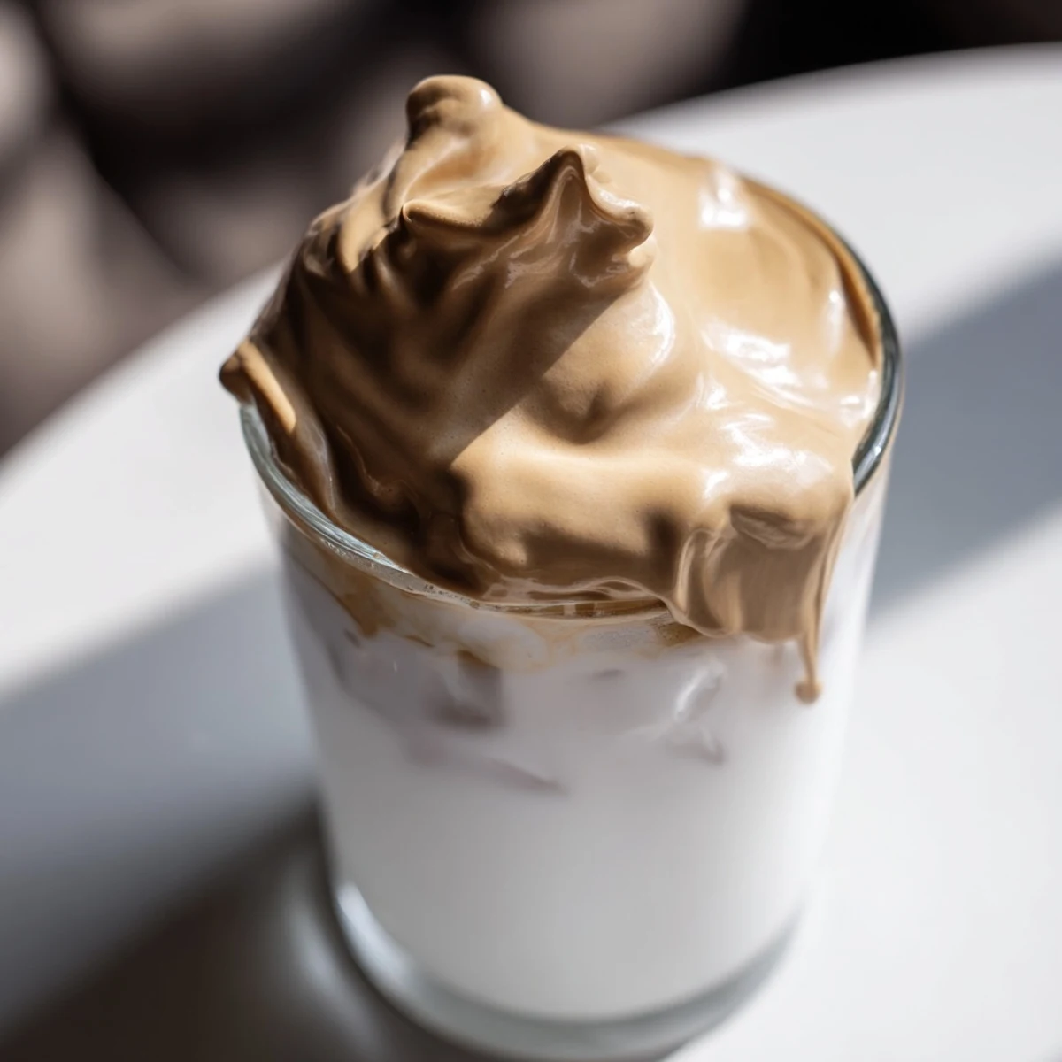 Enjoy homemade Dalgona coffee, a frothy Korean-inspired drink layered in a clear glass for a café-style treat.