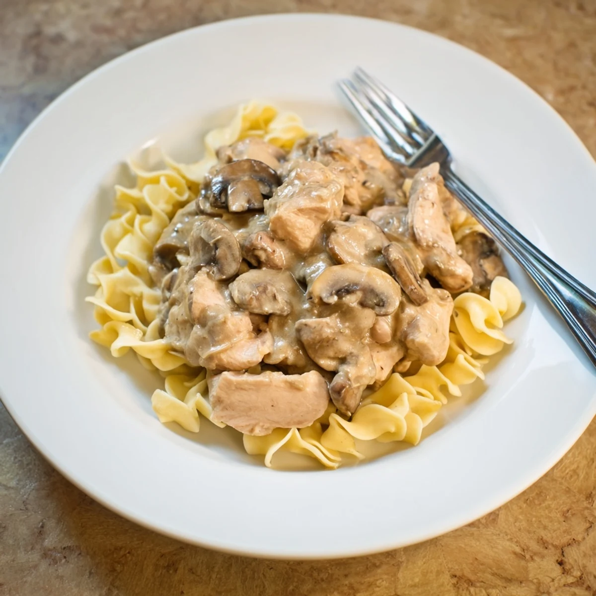 Golden, tender chicken strips and sliced cremini mushrooms simmer in a creamy, paprika-infused sauce over buttery egg noodles for a comforting Chicken and Mushroom Stroganoff.