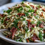 A vibrant bowl of German Cabbage Coleslaw with Shredded Ham, garnished with fresh parsley and ready to serve as a hearty side dish.