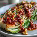 A close-up of tender Baked Cabbage Salad With Winter Romesco topped with fresh parsley and toasted walnuts. 