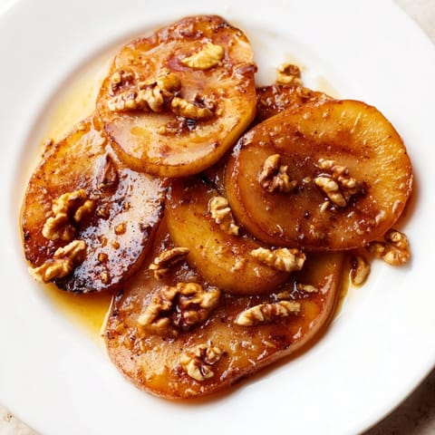 A close-up of Maple-Warm Cozy Plate: Caramelized Pear and Walnut Bake, served warm with creamy vanilla ice cream.