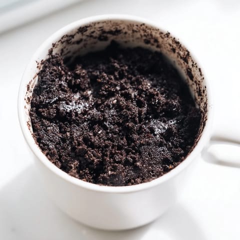 This chocolatey Oreo mug cake is topped with whipped cream, ready to enjoy this instant treat.