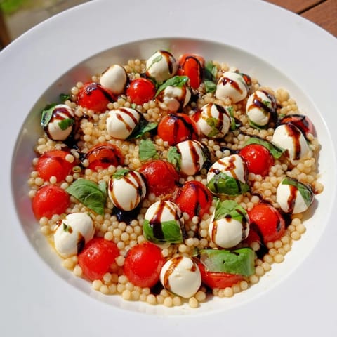 A vibrant Caprese Couscous Salad with juicy tomatoes, creamy mozzarella, and fragrant basil tossed in tangy balsamic glaze.