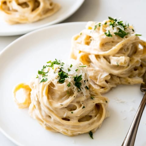 Steaming Easy Creamy Cauliflower Alfredo pasta twirls on a fork with garlic and onion blended sauce.
