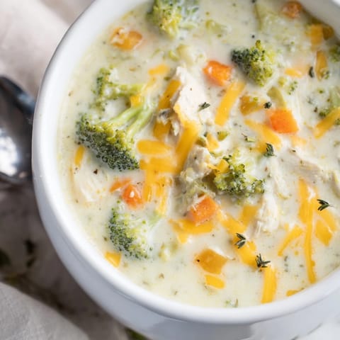 Steaming bowl of homemade chicken broccoli cheddar soup, featuring tender broccoli florets and diced chicken breast.