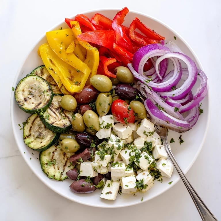 Freshly plated Roasted Greek Salad with cucumbers, feta, and Kalamata olives served alongside crusty bread.