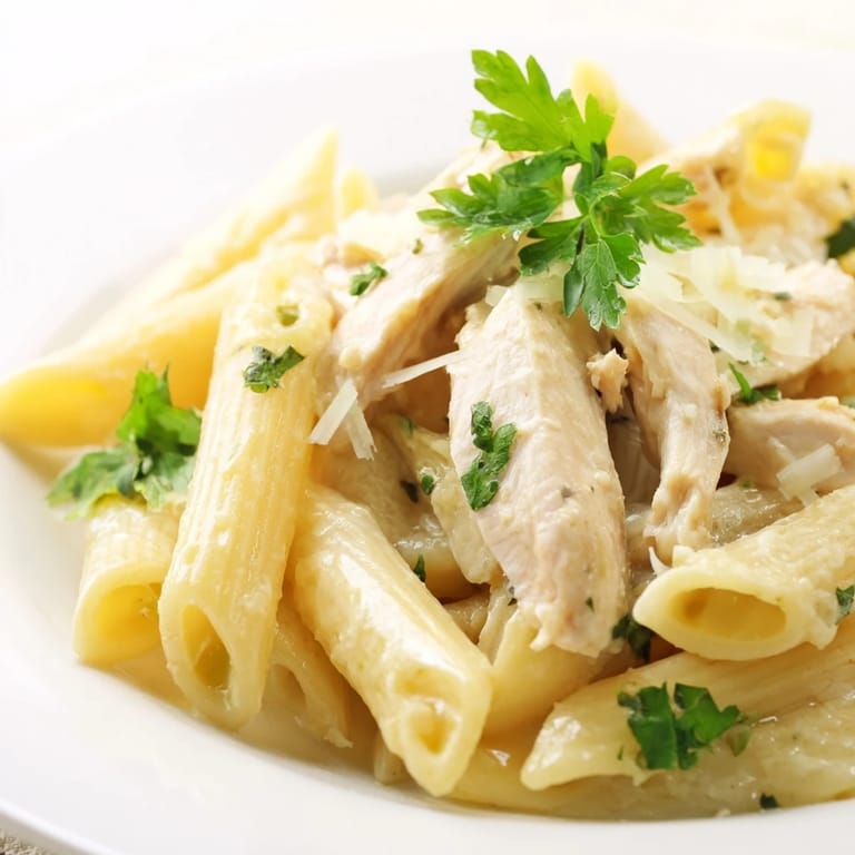 A close-up of Roasted Garlic Chicken Penne garnished with fresh parsley and extra Parmesan for a vibrant touch.  