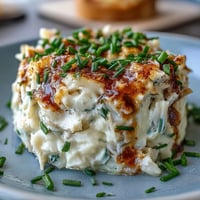 Creamy crab-filled deviled eggs topped with Old Bay seasoning, garnished with fresh chives and lemon wedges for a zesty appetizer.